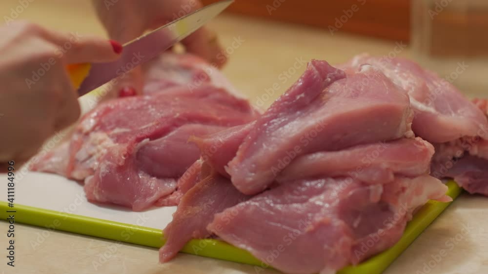 Woman cuts raw meat evening kitchen interior closeup Woman cuts raw meat evening kitchen interior closeup