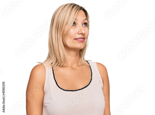 Middle age caucasian woman wearing casual clothes looking away to side with smile on face, natural expression. laughing confident.