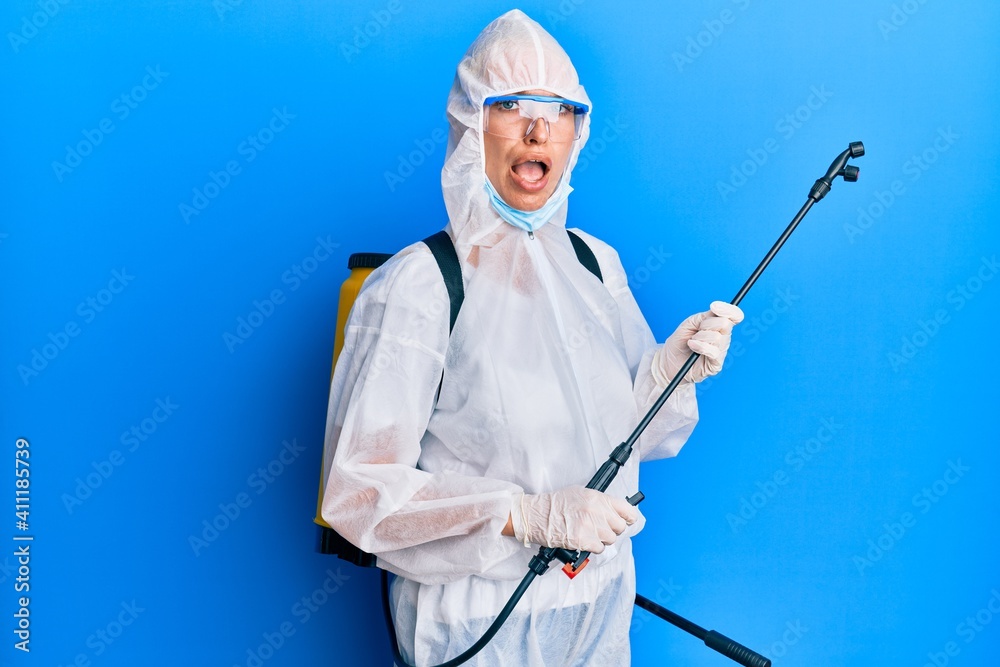Young blonde girl wearing covid-19 equipment in shock face, looking skeptical and sarcastic, surprised with open mouth Young blonde girl wearing covid-19 equipment in shock face, looking skeptical and sarcastic, surprised with open mouth