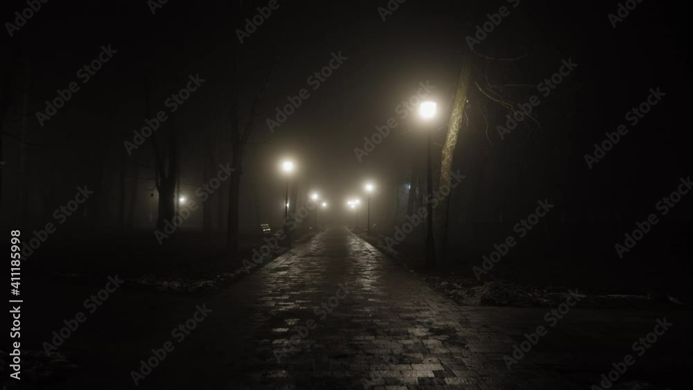 Night city scene, empty dark foggy park lit by lanterns at midnight, slow-motion shot