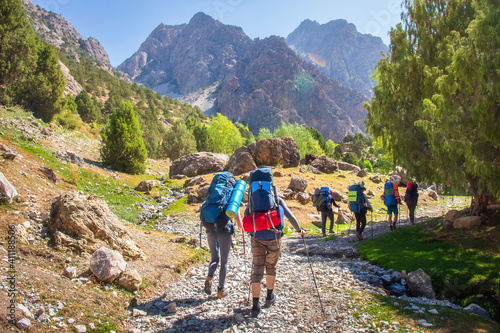 Obraz na płótnie Hikers with backpacks walking in mountains. Group of friends in Fann mountains, Tajikistan. Mountain trail. Tourists hiking. w salonie