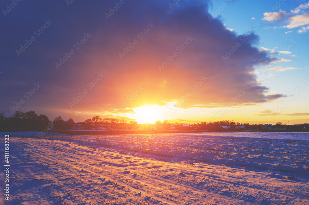 Rural landscape in winter. The snow-covered field at sunset