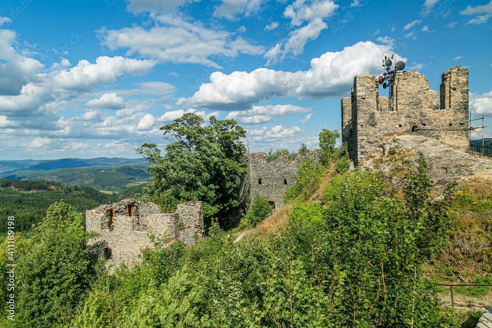 Obraz premium Andelska hora, Czech Republic - August 11 2018: Remains of the stone castle from 15th century standing on a hill with green trees and scenic view into the countryside. Sunny summer day with blue sky.
