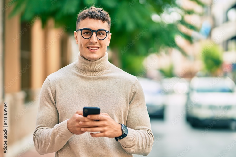 Young hispanic man wearing glasses using smartphone at the city. Young hispanic man wearing glasses using smartphone at the city.