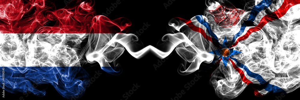 Netherlands vs Assyria smoky mystic flags placed side by side. Thick colored silky abstract smoke flags.