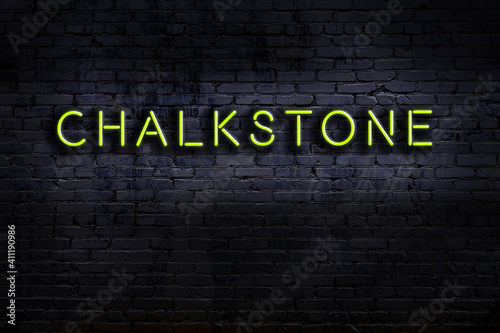 Night view of neon sign on brick wall with inscription chalkstone photo