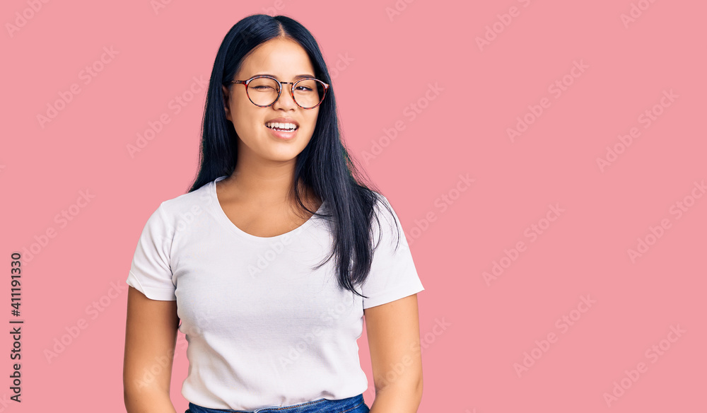 Young beautiful asian girl wearing casual clothes and glasses winking looking at the camera with sexy expression, cheerful and happy face. Young beautiful asian girl wearing casual clothes and glasses winking looking at the camera with sexy expression, cheerful and happy face.