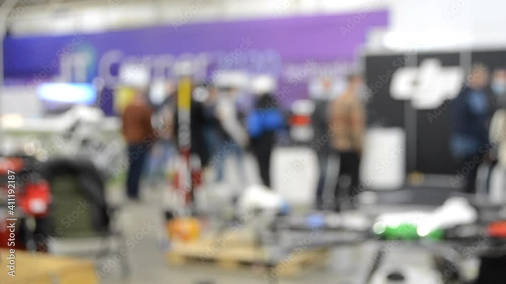 Blurred background. People walk inside large space building. Exhibition presentation. Abstract background and bokeh spots with moving people indoors. Hall, lobby, entry. People walk inside space. Blurred background. People walk inside large space building. Exhibition presentation. Abstract background and bokeh spots with moving people indoors. Hall, lobby, entry. People walk inside space.
