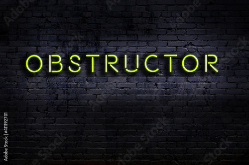 Neon sign. Word obstructor against brick wall. Night view photo