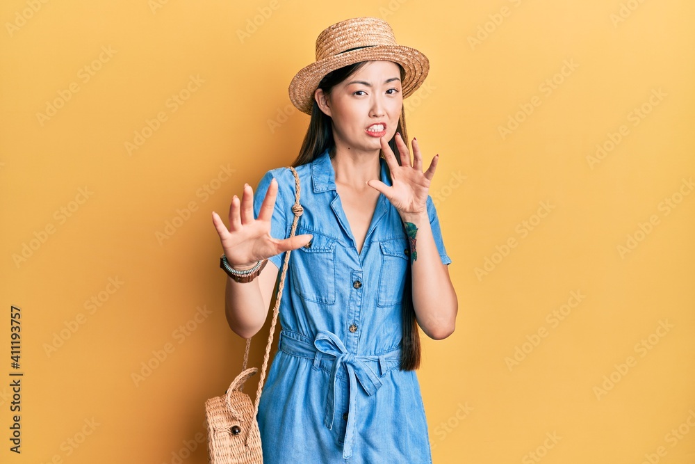 Young chinese woman wearing summer hat afraid and terrified with fear expression stop gesture with hands, shouting in shock. panic concept. Young chinese woman wearing summer hat afraid and terrified with fear expression stop gesture with hands, shouting in shock. panic concept.