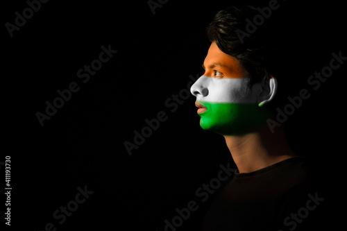 Fotografi man looking sideways with tricolour painted on his face, independence day