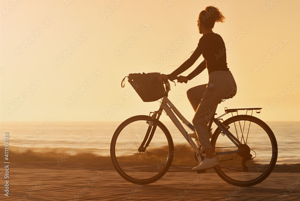 Fototapeta premium Woman traveler with her bicycle rides on sea coastline and looking on beautifull sunset sky in sunny summer day on beach