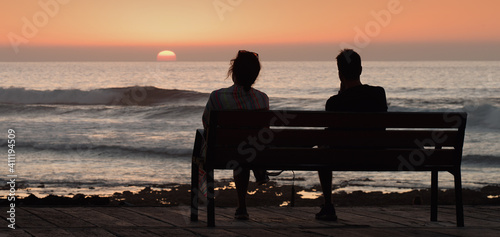 Silhouette romantic couple on a bench by the sea