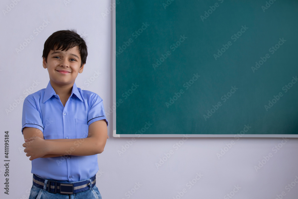 school boy standing in front of blackboard	