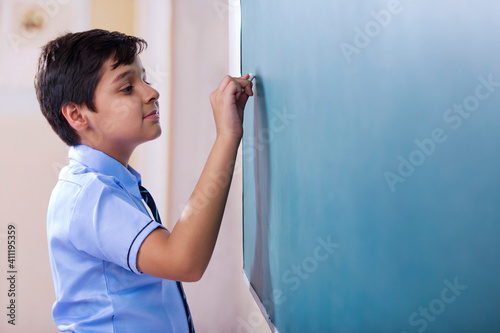 school boy solving question on blackboard 