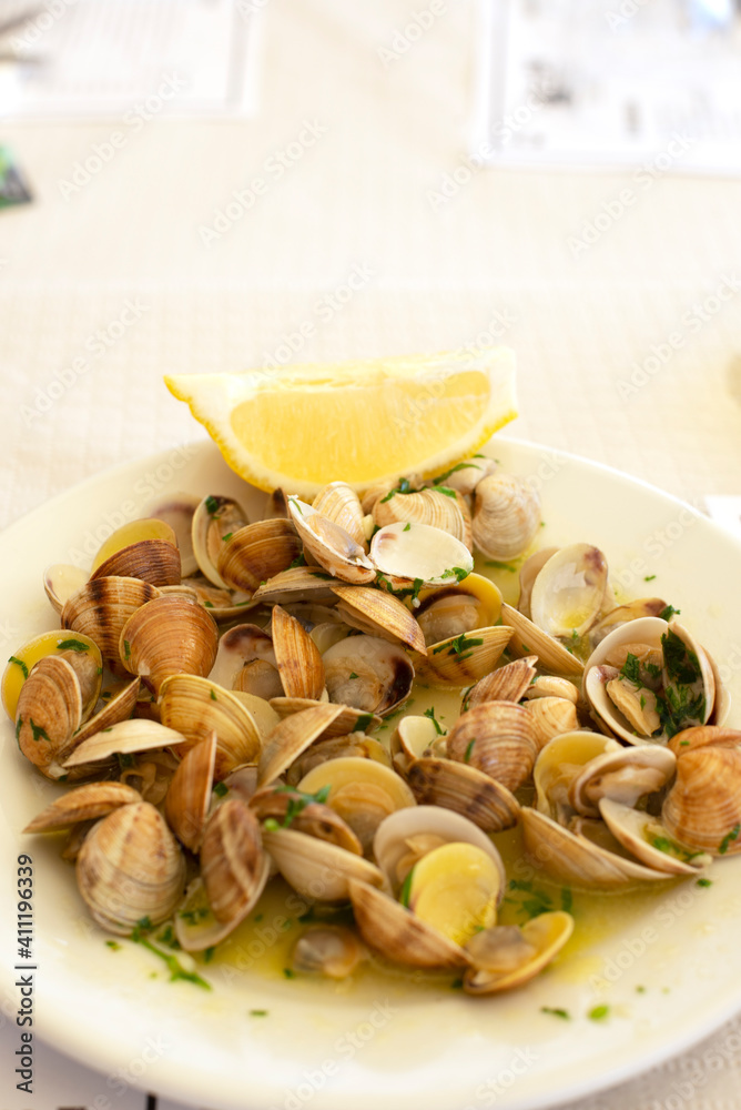 Restaurante con comida típica española con plato de almejas cocinadas y limón en la Costa del Sol en Andalucía Restaurante con comida típica española con plato de almejas cocinadas y limón en la Costa del Sol en Andalucía