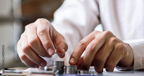 A close-up view of a businessman using two hands to stack coins in a row, he always invested his money to grow more. The idea of bringing money to pass the money.