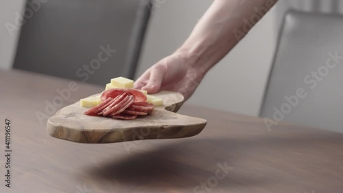 Slow motion man put olive board with vintage cheese and salae on walnut table photo