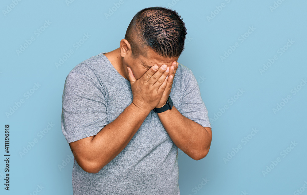 Young latin man wearing casual clothes with sad expression covering face with hands while crying. depression concept. Young latin man wearing casual clothes with sad expression covering face with hands while crying. depression concept.