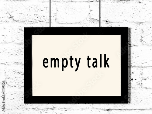 Black frame hanging on white brick wall with inscription empty talk