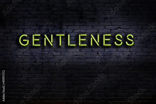 Neon sign. Word gentleness against brick wall. Night view