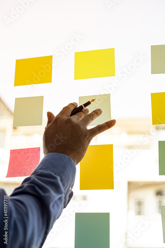 фотографія Business men are writing on a post-it that is placed in the glass of the conference room to brainstorm the ideas of the operations of the company together to grow the business
