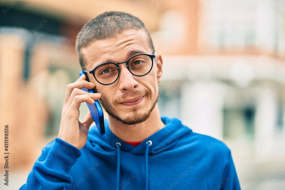 Young hispanic man with relaxed expression talking on the smartphone at the city. Young hispanic man with relaxed expression talking on the smartphone at the city.