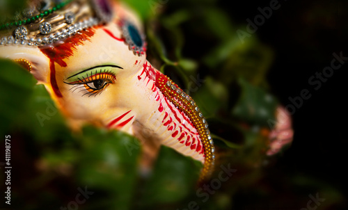 Fototapeta Naklejka Na Ścianę i Meble -  top shot of lord ganesha idol with leaf garland	