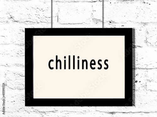 Fotografie Black frame hanging on white brick wall with inscription chilliness