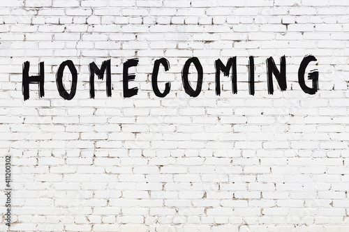Inscription homecoming painted on white brick wall photo