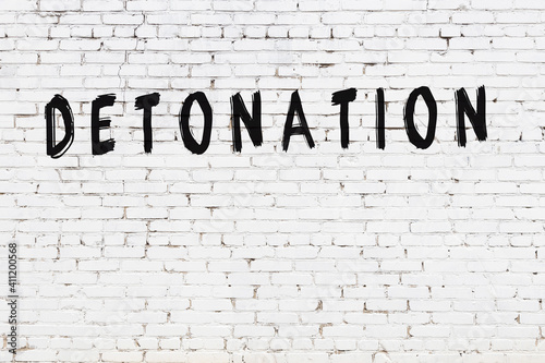 Konstfotografi White wall with black paint inscription detonation on it
