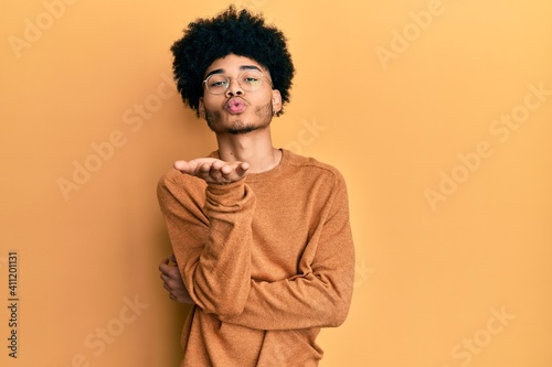 Young african american man with afro hair wearing casual winter sweater looking at the camera blowing a kiss with hand on air being lovely and sexy. love expression. © Krakenimages.com