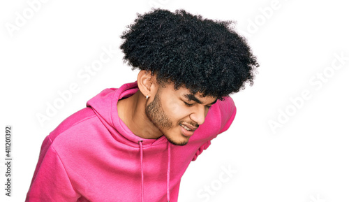 Young african american man with afro hair wearing casual pink sweatshirt suffering of backache, touching back with hand, muscular pain
