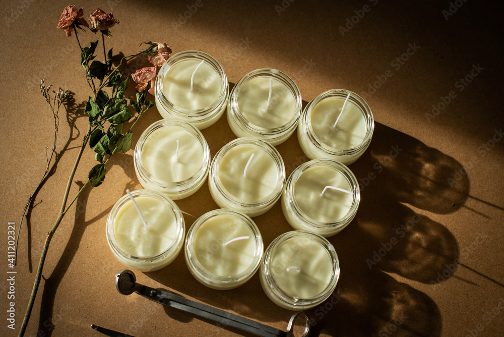 Handmade candle from paraffin and soy wax in glass with flowers and tools on craft background. Let flay. Candle making Handmade candle from paraffin and soy wax in glass with flowers and tools on craft background. Let flay. Candle making