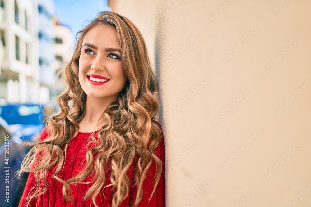 Fototapeta premium Young blonde girl smiling happy leaning on the wall at the city.