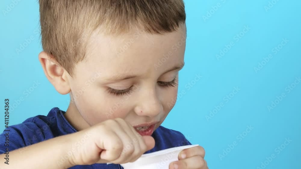 Little boy eatiing yogurt on blue background. Little boy eatiing yogurt on blue background.