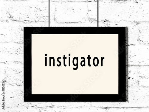 Black frame hanging on white brick wall with inscription instigator photo