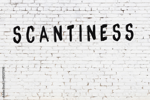 White wall with black paint inscription scantiness on it
