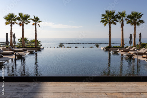Pool and sun loungers in a luxury resort with palms on the coast on a sunny day