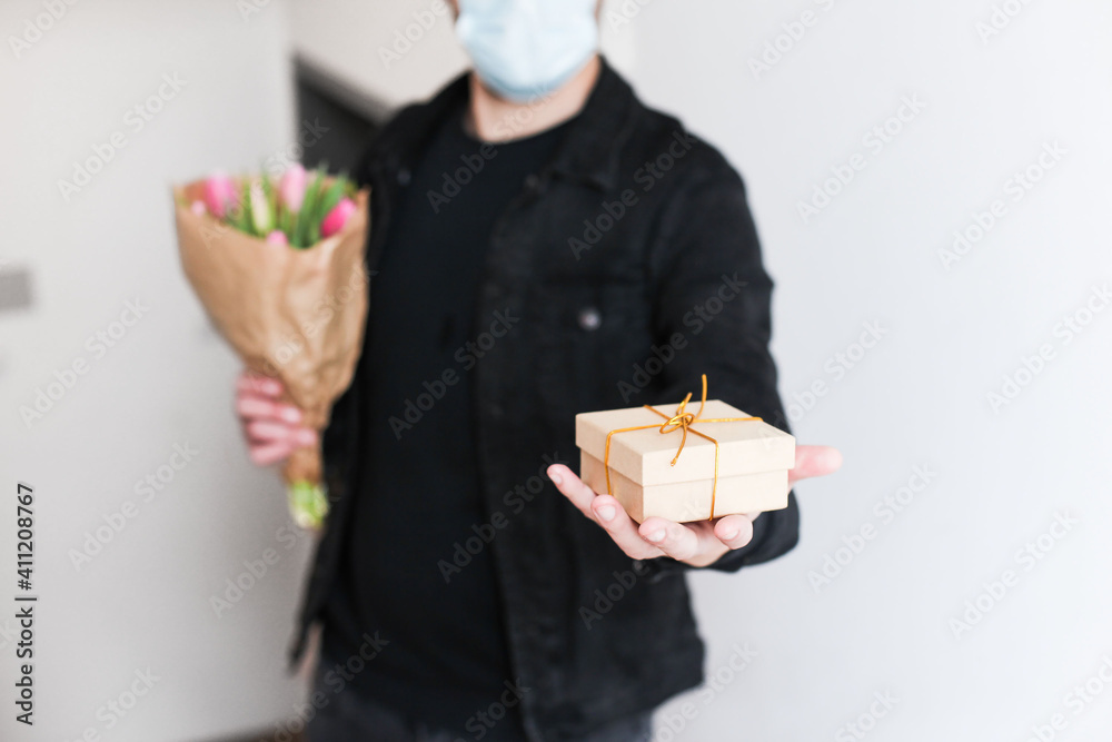 A man in medical mask delivering a gift box and a craft bouquet during the pandemic A man in medical mask delivering a gift box and a craft bouquet during the pandemic