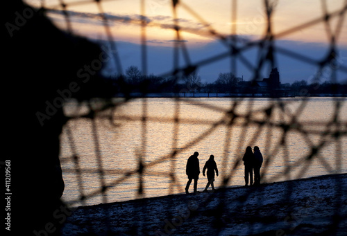 Spaziergänger am Elbstrand in Hamburg gesehen durch ein Gitter