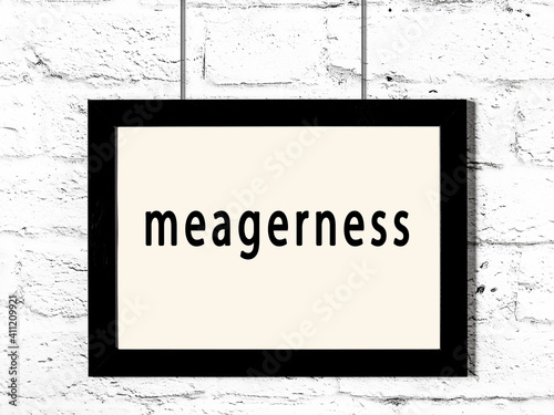 Black frame hanging on white brick wall with inscription meagerness