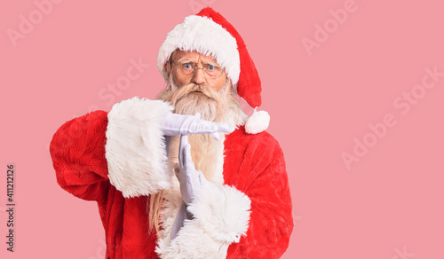 Old senior man with grey hair and long beard wearing traditional santa claus costume doing time out gesture with hands, frustrated and serious face