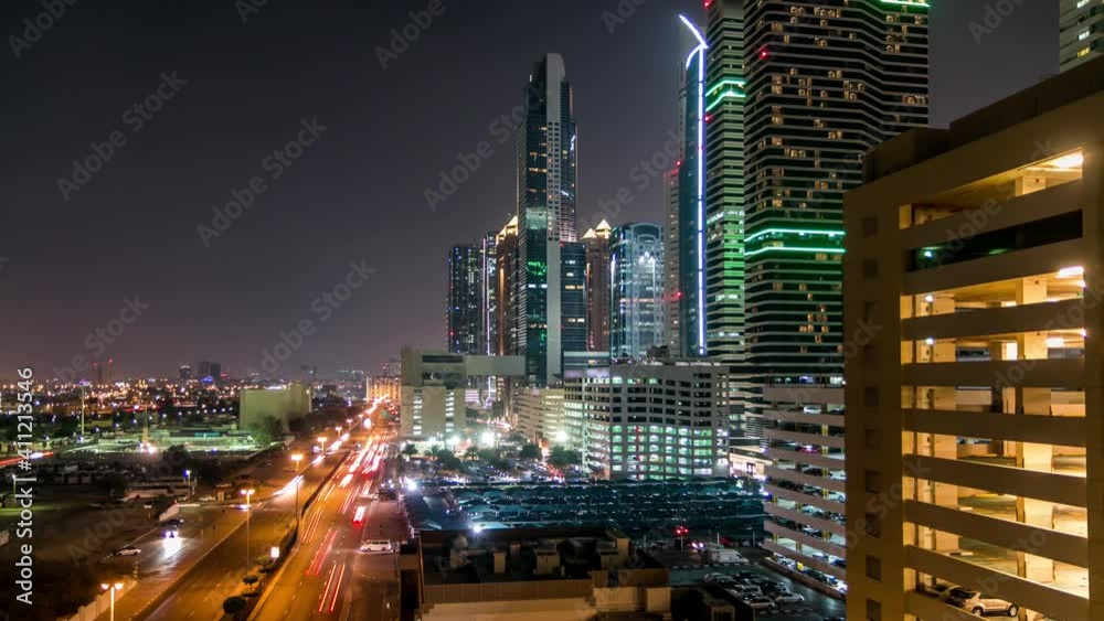 Downtown Dubai towers night timelapse. Aerial view of Sheikh Zayed road with skyscrapers. Traffic on the road and cars on parking. Blinking lights and trails Downtown Dubai towers night timelapse. Aerial view of Sheikh Zayed road with skyscrapers. Traffic on the road and cars on parking. Blinking lights and trails