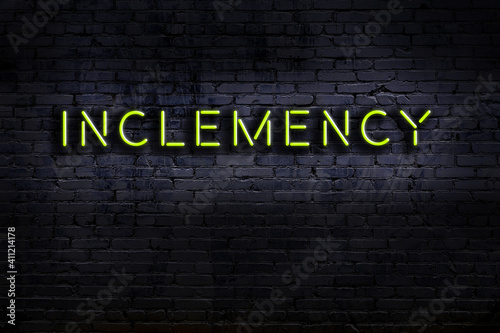 Neon sign. Word inclemency against brick wall. Night view