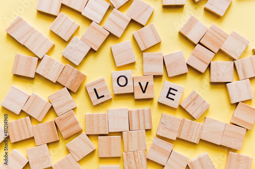 Pile of wooden letters on the surface of a yellow background with spell love  valentine s day. Selective focus