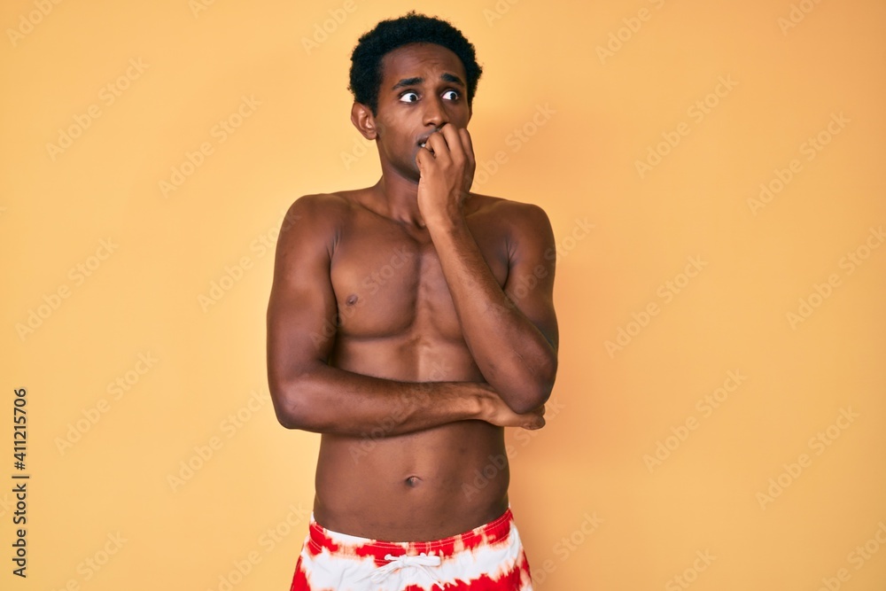 African handsome man wearing swimsuit looking stressed and nervous with hands on mouth biting nails. anxiety problem.
