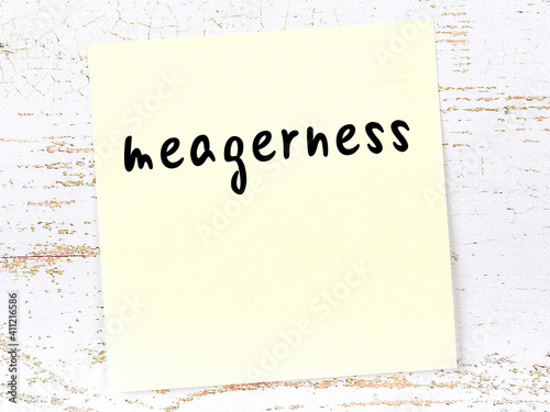 Yellow sheet of paper with word meagerness. Reminder concept photo