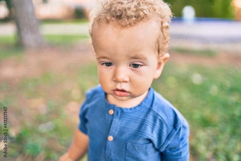 Cute and happy little boy having fun at the park on a sunny day. Beautiful blonde hair male toddler playing outdoors Cute and happy little boy having fun at the park on a sunny day. Beautiful blonde hair male toddler playing outdoors