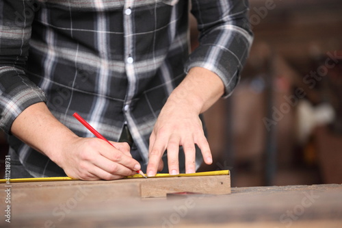 Carpenter, he is working in the workshop. Man at work on wood. Image of mature carpenter in the workshop, furniture making concept.